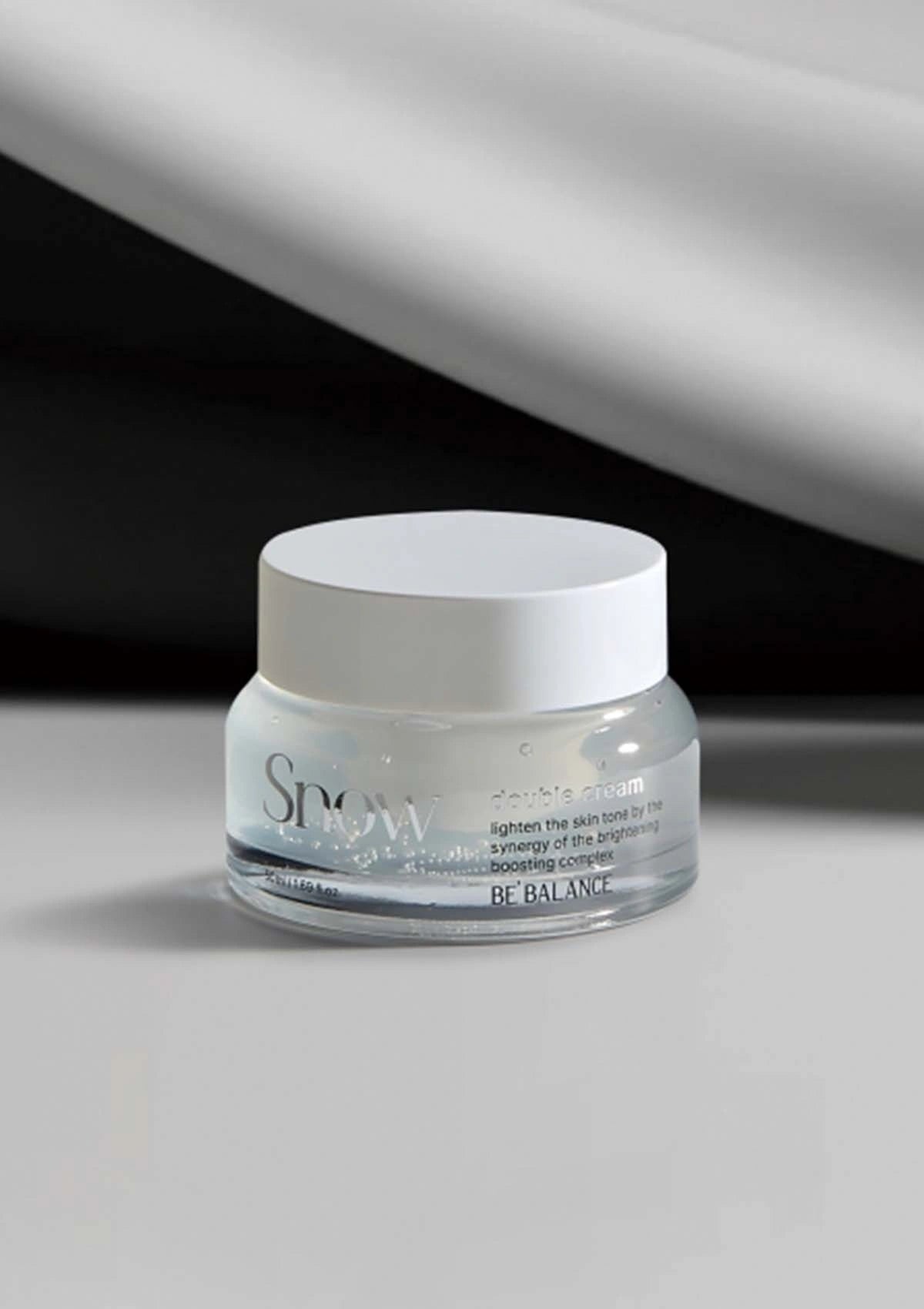 Skincare jar labeled 'Snow' on a gray background